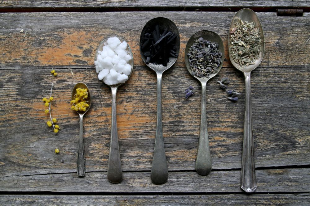 Dried herbs and spices arranged in wooden spoons on a rustic table