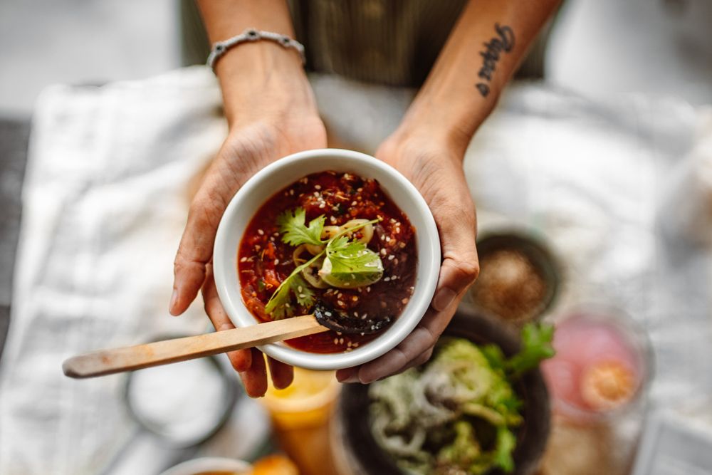 Hands holding a freshly prepared bowl topped with herbs